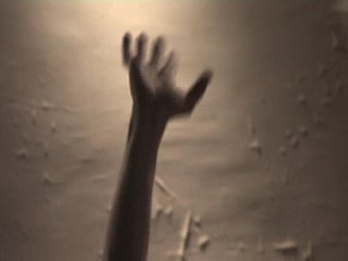 main tendue vers le ciel devant un mur cloqué